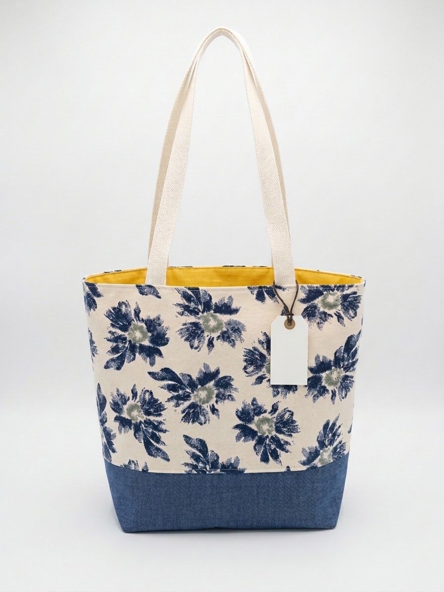 Large tote with blue painted daisies on natural canvas, a denim base and yellow lining